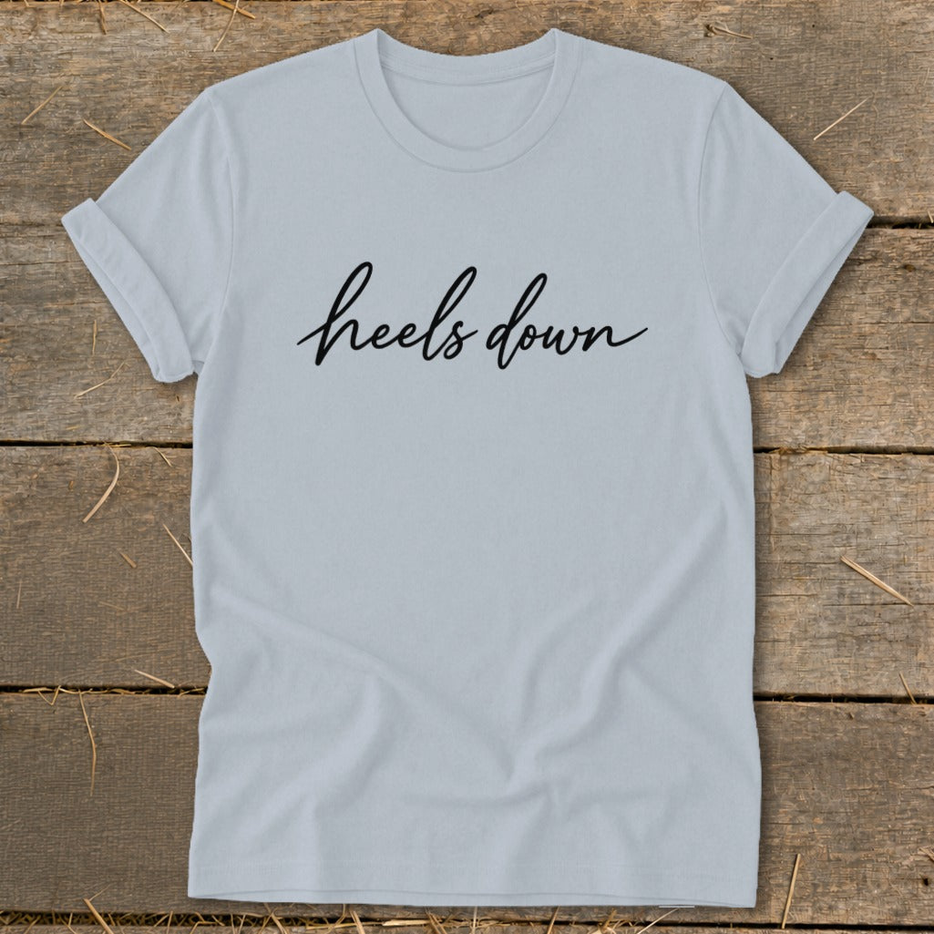 Light blue t-shirt with black script text that reads "heels down".