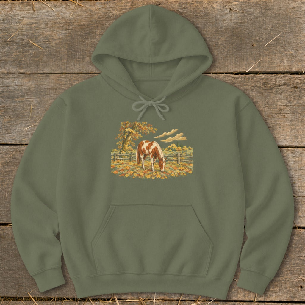 Green hoodie with a brown and white horse grazing in an autumn field.