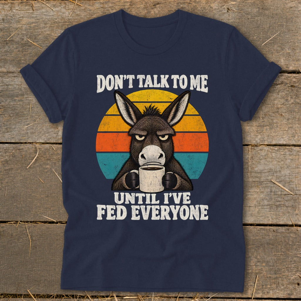 Navy blue t-shirt featuring a grumpy donkey drinking coffee in front of a retro sunset graphic.