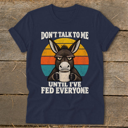 Navy blue t-shirt featuring a grumpy donkey drinking coffee in front of a retro sunset graphic.