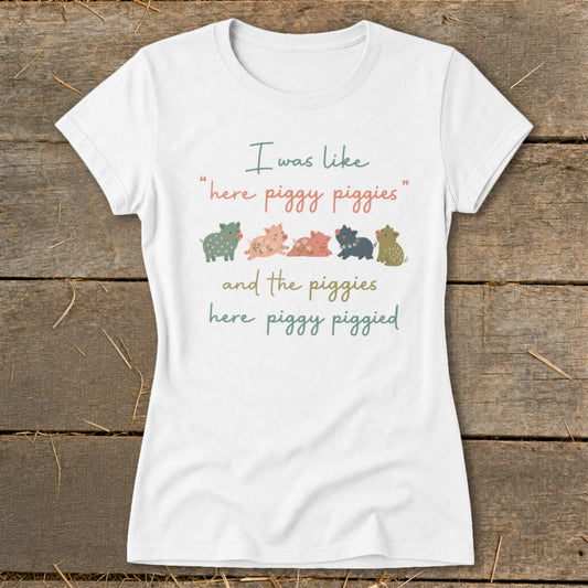 White t-shirt with text "I was like 'here piggy piggies' and the piggies here piggy piggied" and five cartoon pigs.