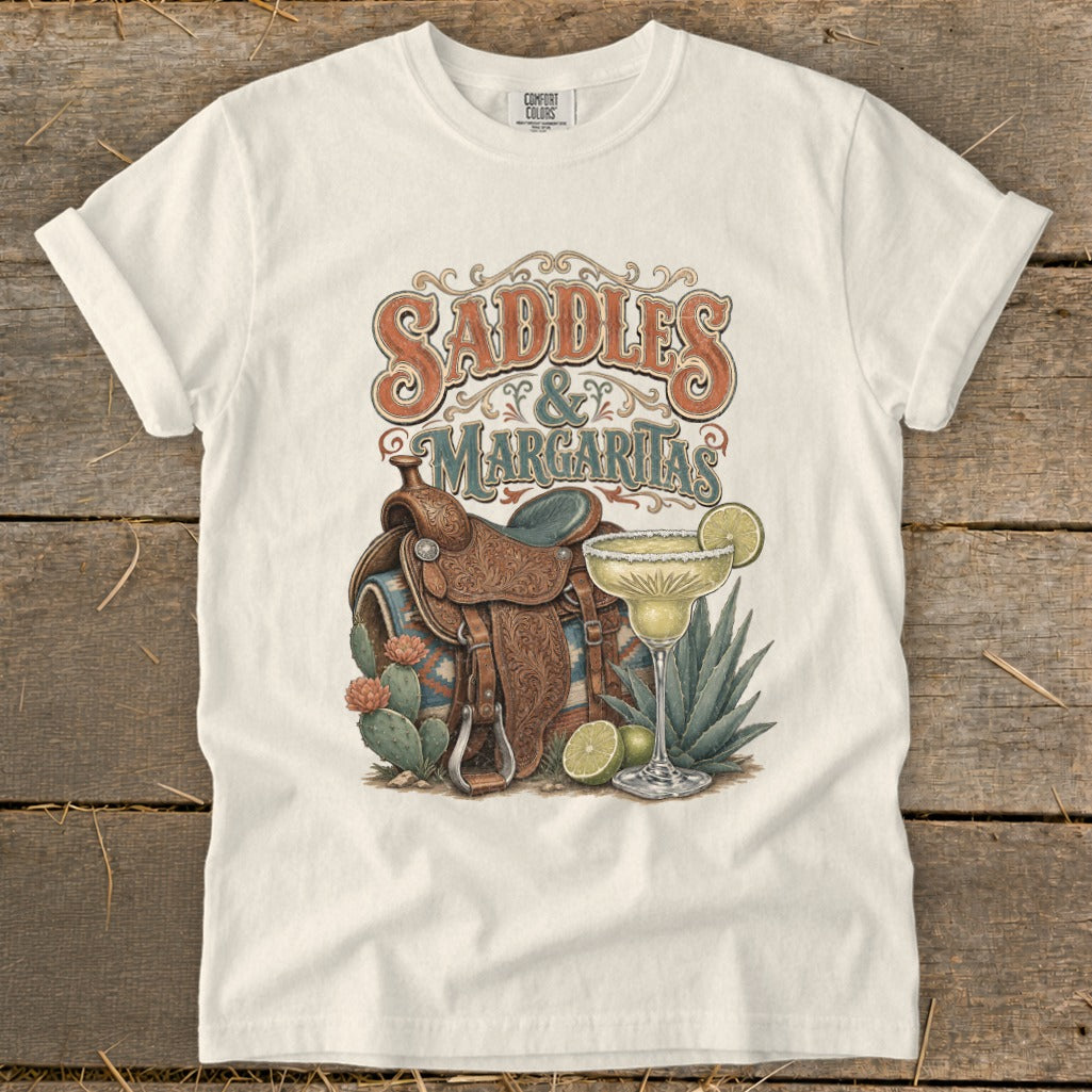 White t-shirt with "Saddles & Margaritas" graphic featuring a saddle, margarita, and cacti.