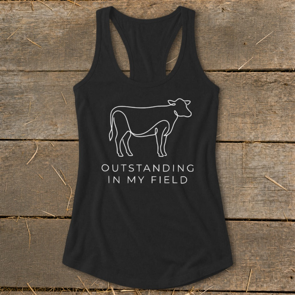 Black tank top with white line art cow and text "OUTSTANDING IN MY FIELD."