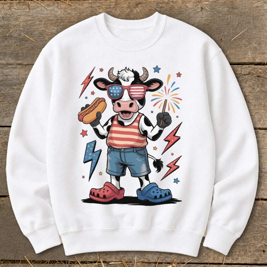 Cartoon cow wearing American flag sunglasses holding hot dog, with fireworks.