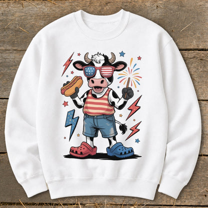 Cartoon cow wearing American flag sunglasses holding hot dog, with fireworks.