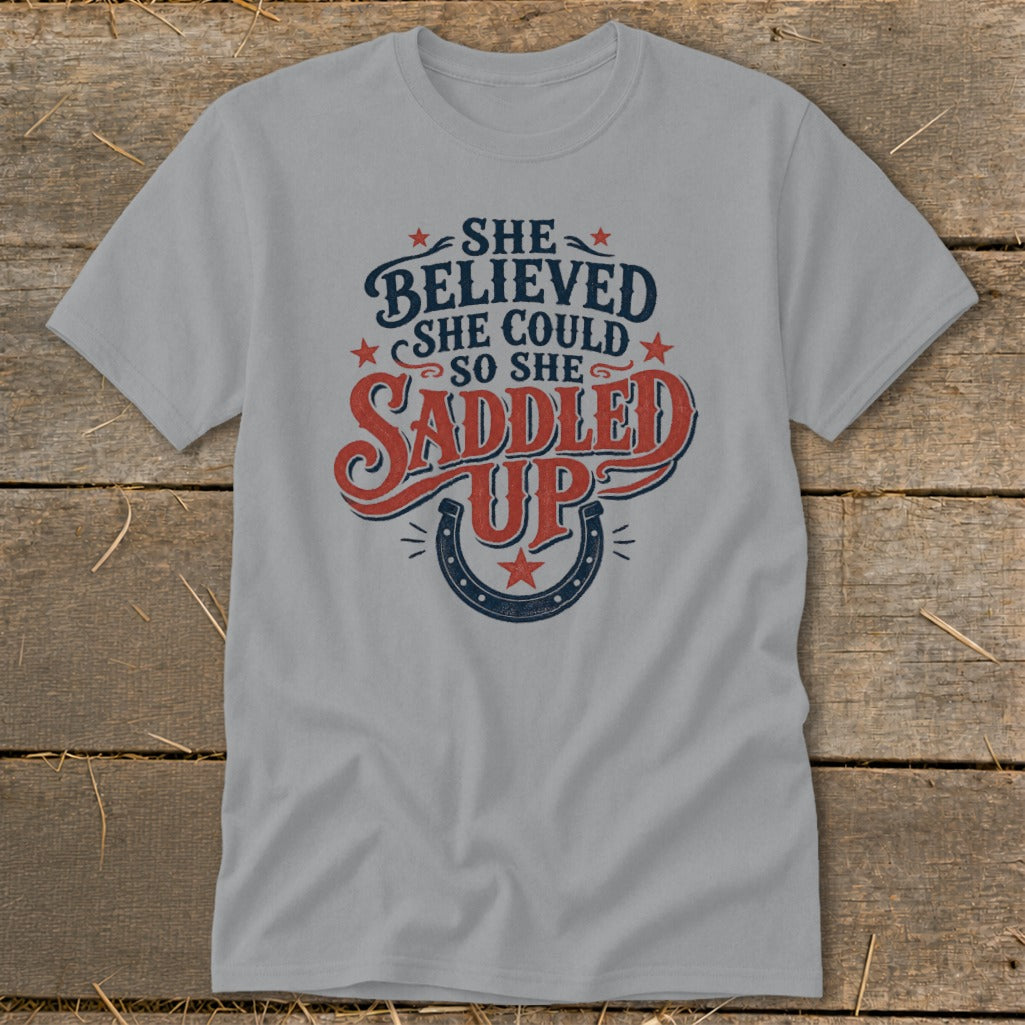Grey t-shirt with "She Believed She Could So She Saddled Up" text and horseshoe graphic.