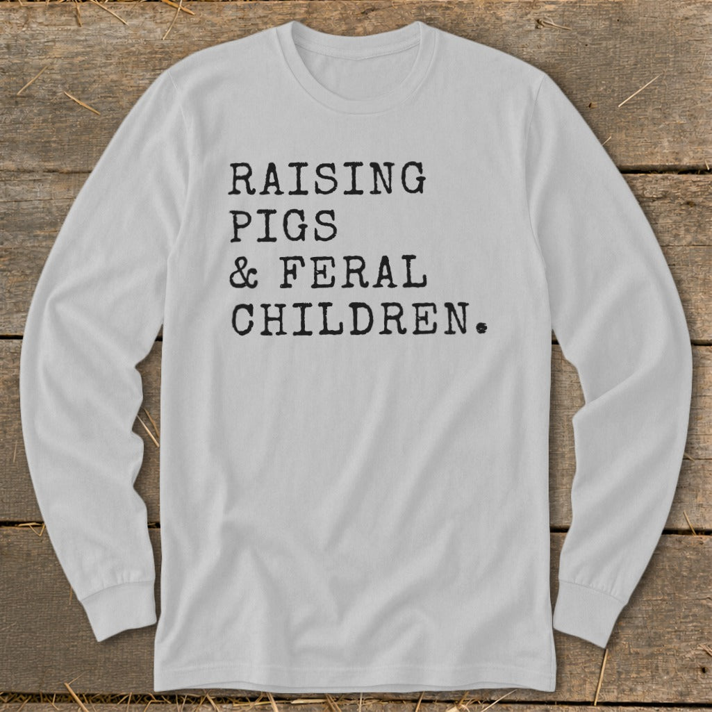 White long-sleeve shirt with black text reading "RAISING PIGS & FERAL CHILDREN."