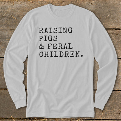 White long-sleeve shirt with black text reading "RAISING PIGS & FERAL CHILDREN."