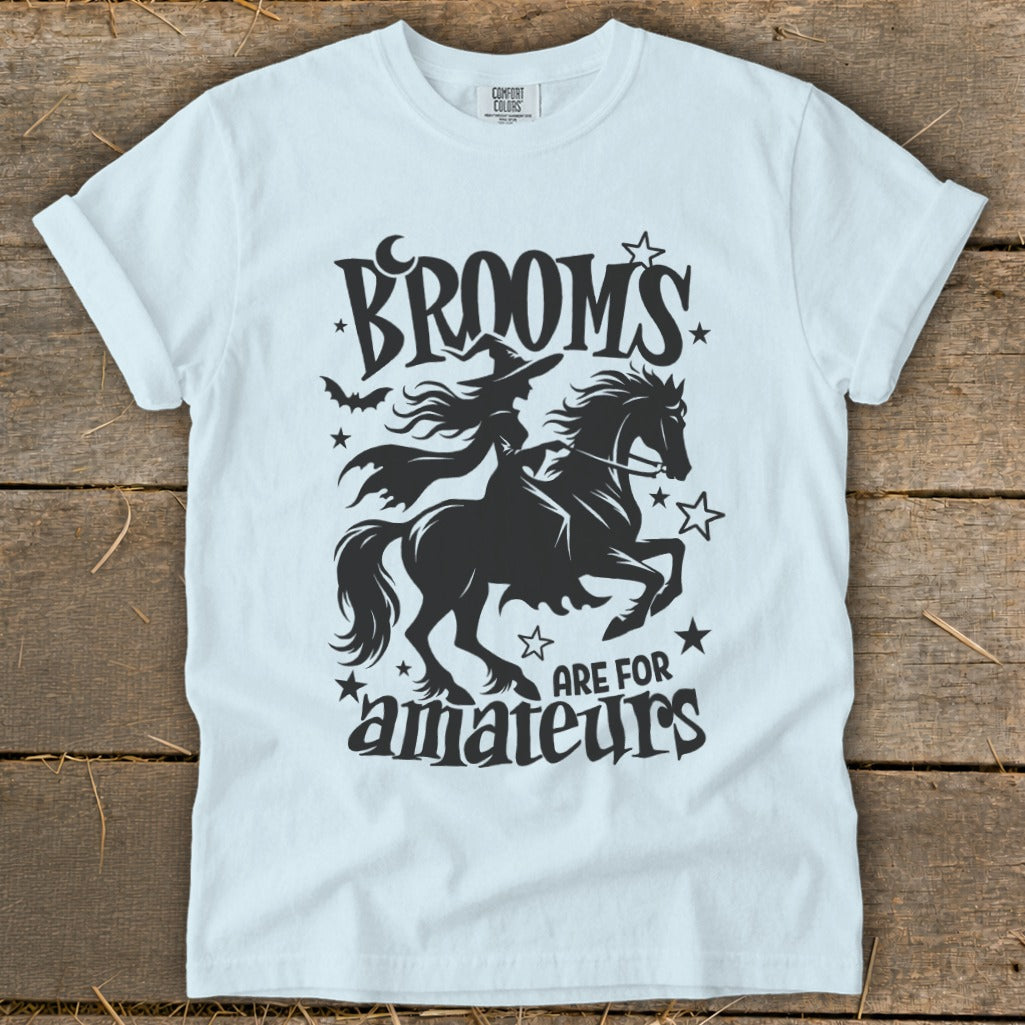 Light blue t-shirt with black graphic of witch riding horse, "Brooms are for amateurs."