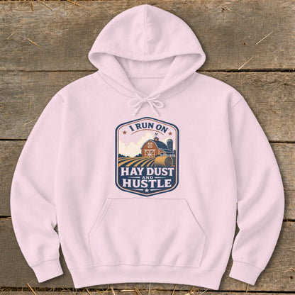 Pink hoodie with a graphic reading "I run on hay dust and hustle."