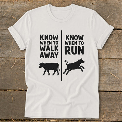 White t-shirt with text "KNOW WHEN TO WALK AWAY" and "KNOW WHEN TO RUN" and cow graphics.