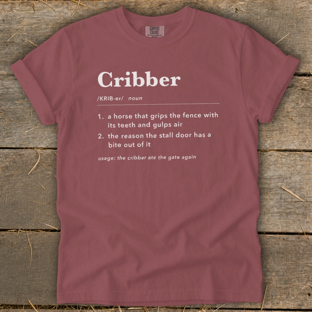 A red crewneck t-shirt featuring dictionary-style definitions for the word Cribber printed in white.