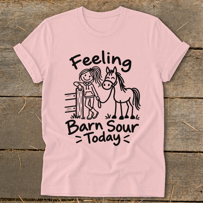 Pink t-shirt with black graphic: girl leaning on fence with horse, text "Feeling Barn Sour Today".