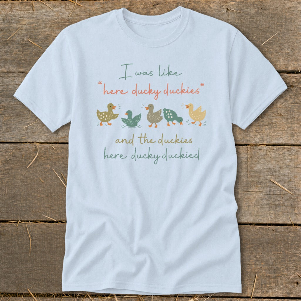 Light blue t-shirt with text and a row of five colorful ducks.