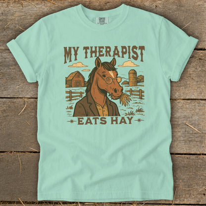 Horse wearing glasses and a jacket, eating hay with text "MY THERAPIST EATS HAY".