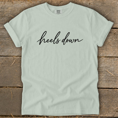 Light green t-shirt with "heels down" in black script text.