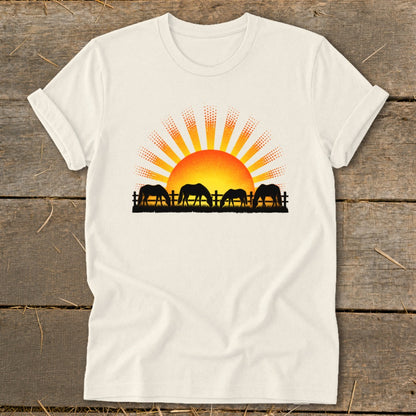 Cream t-shirt with silhouetted horses grazing in front of a sunrise graphic.