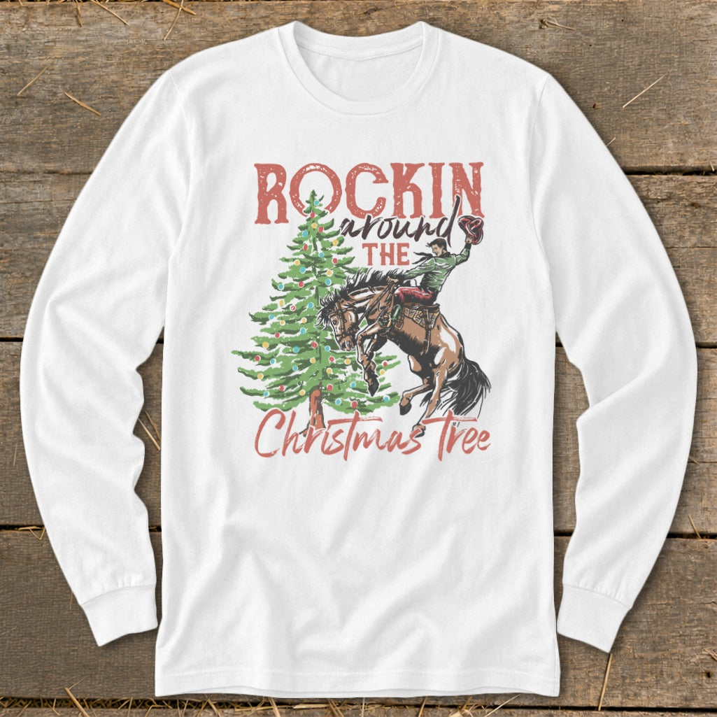 White long-sleeve shirt with a rodeo rider and Christmas tree graphic that reads "Rockin Around The Christmas Tree."