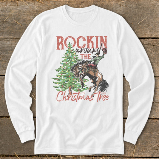 White long-sleeve shirt with a rodeo rider and Christmas tree graphic that reads "Rockin Around The Christmas Tree."