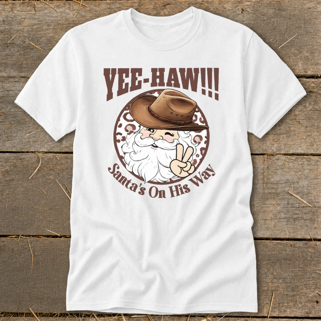 White t-shirt with Santa wearing a cowboy hat, text "Yee-Haw!!!" and "Santa's On His Way".