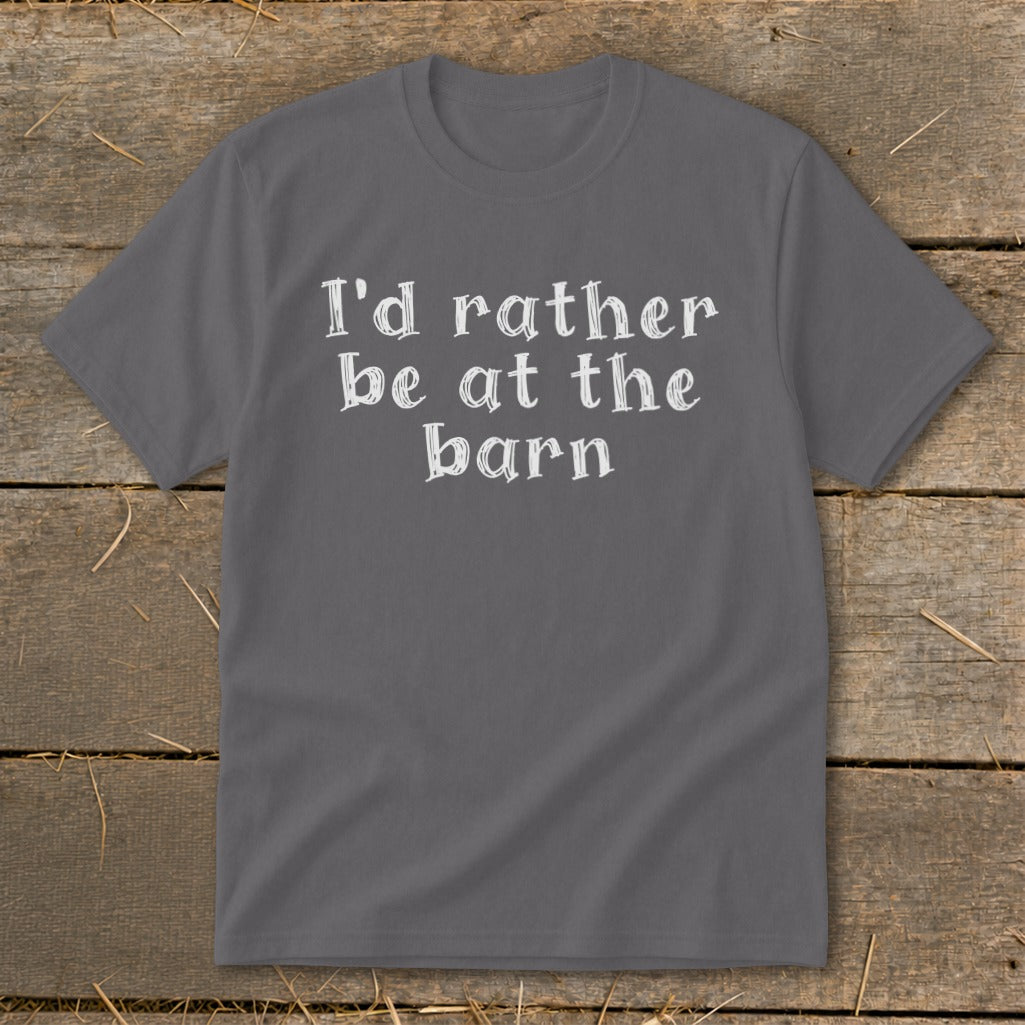 Gray t-shirt with white text "I'd rather be at the barn" on a wooden background.
