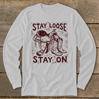 Long sleeve shirt with a cowboy saddle, boots, and "STAY LOOSE STAY ON" text.